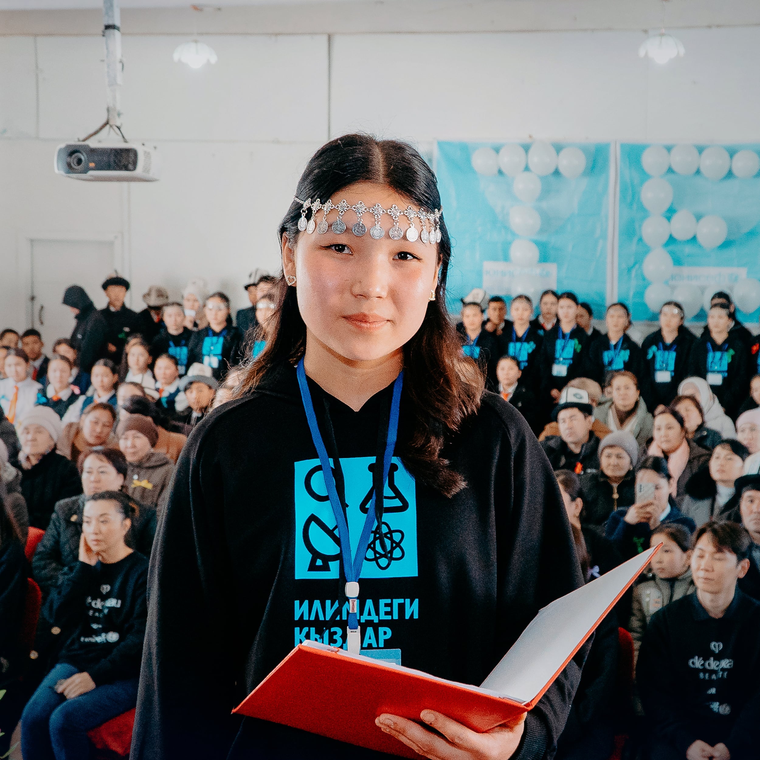 Photo of a girl holding a red notebook in Kyrgyzstan, taken during Cl&eacute; de Peau Beaut&eacute;&rsquo;s 2025 UNICEF partnership visit.